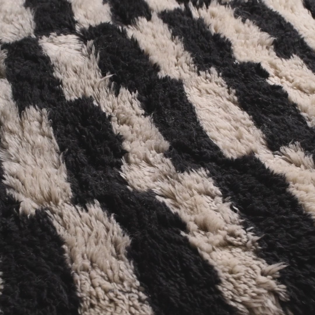 Close-up of a black and white handwoven Moroccan shag rug, showcasing traditional Berber patterns