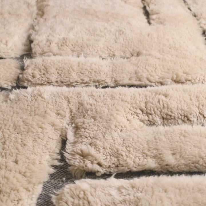Close-up of a textured shag wool Moroccan rug with abstract black lines, showcasing traditional Berber craftsmanship.