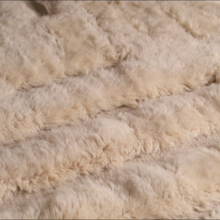 Close-up of a textured cream Geometric Beni Mrirt Moroccan wool rug, showcasing intricate traditional Berber patterns and softness.
