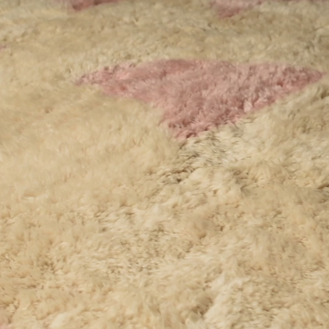 Soft pink geometric wool Moroccan rug with ivory base, showcasing playful abstract design and traditional craftsmanship.