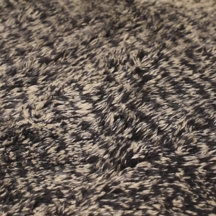 Close-up of a Handmade Beni Mrirt Moroccan wool rug in black and ivory, featuring a plush and textured design.