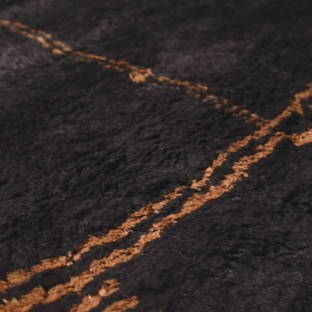 Dark charcoal Moroccan wool rug with golden abstract patterns, handmade and richly textured. Ideal for adding warmth and style.