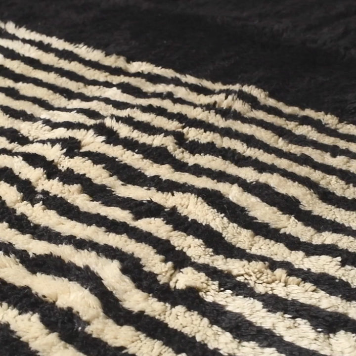 Handwoven Moroccan rug with black and white geometric design, crafted from wool, perfect for modern or traditional interiors.