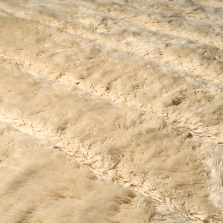Close-up of cream handmade Moroccan Beni Mrirt wool rug with geometric pattern, showcasing plush texture.