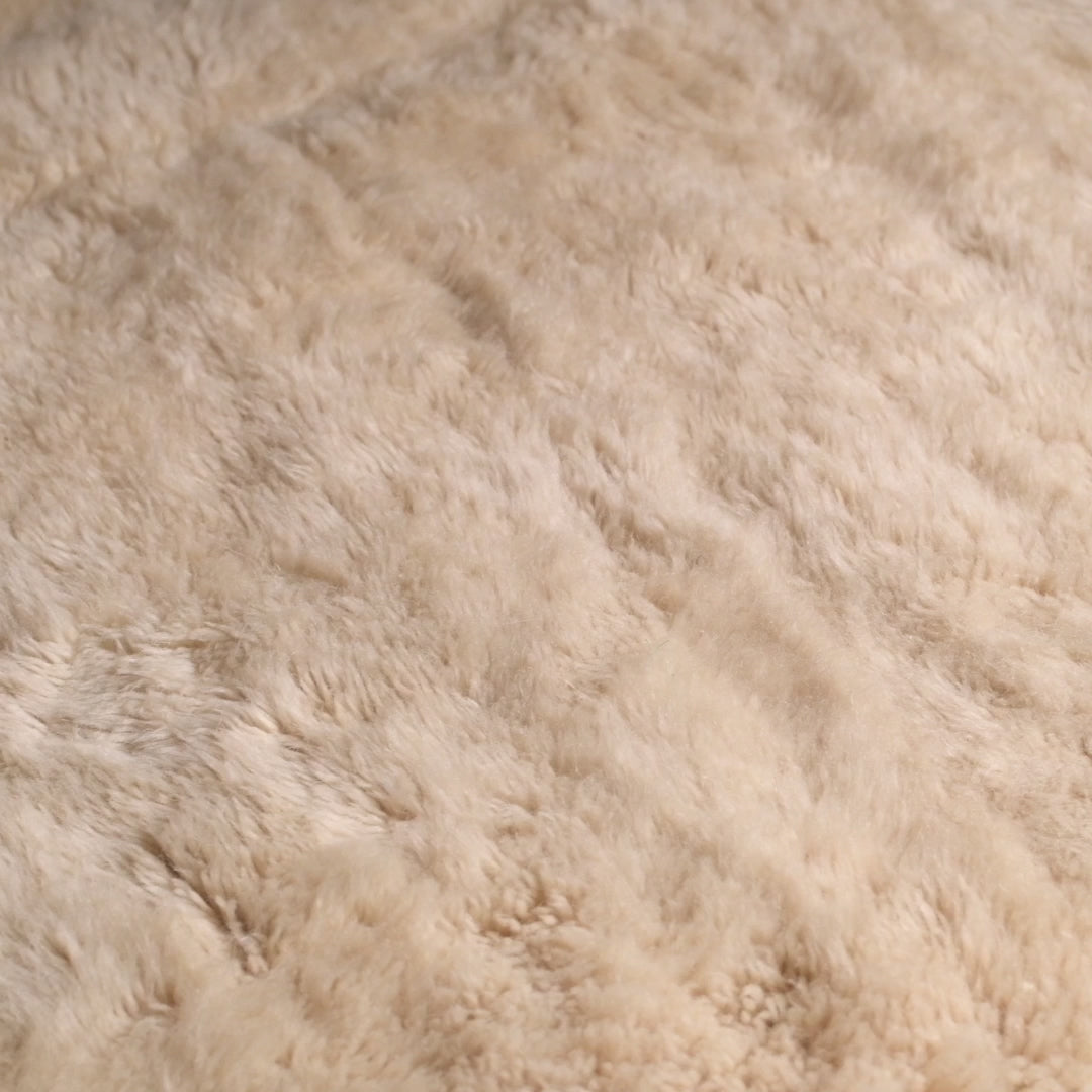 Close-up of a plush creamy beige Moroccan Beni Mrirt rug, handcrafted from soft natural wool, featuring a subtle X-shaped design.