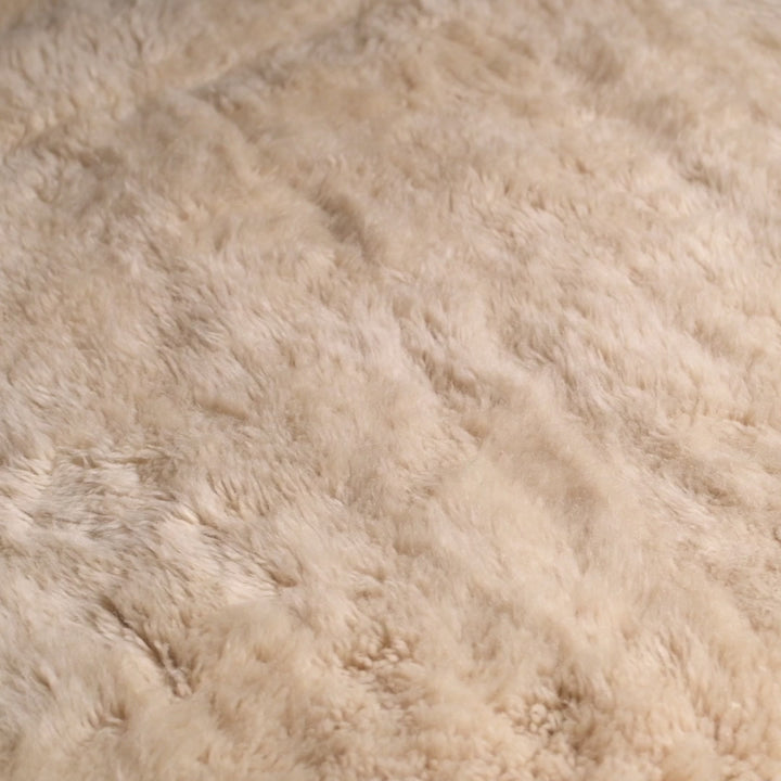 Close-up of a plush creamy beige Moroccan Beni Mrirt rug, handcrafted from soft natural wool, featuring a subtle X-shaped design.