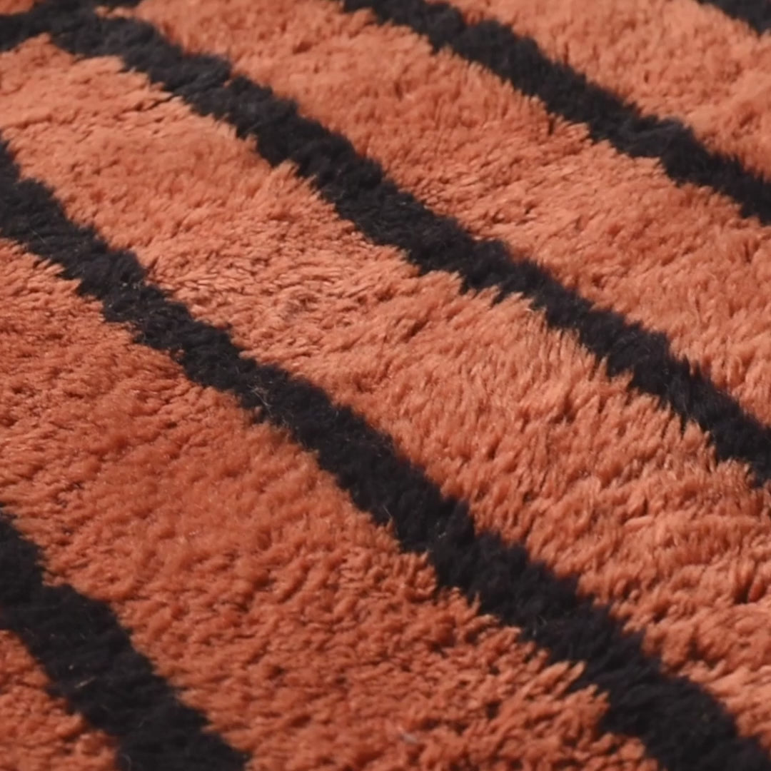 Close-up of a handcrafted Moroccan runner rug with a black striped pattern on textured wool.