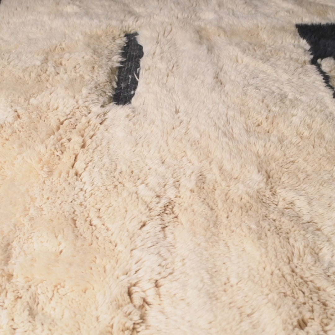 Close-up of black and ivory Moroccan wool rug with checkerboard pattern, handwoven by Berber artisans, ideal for modern interiors.