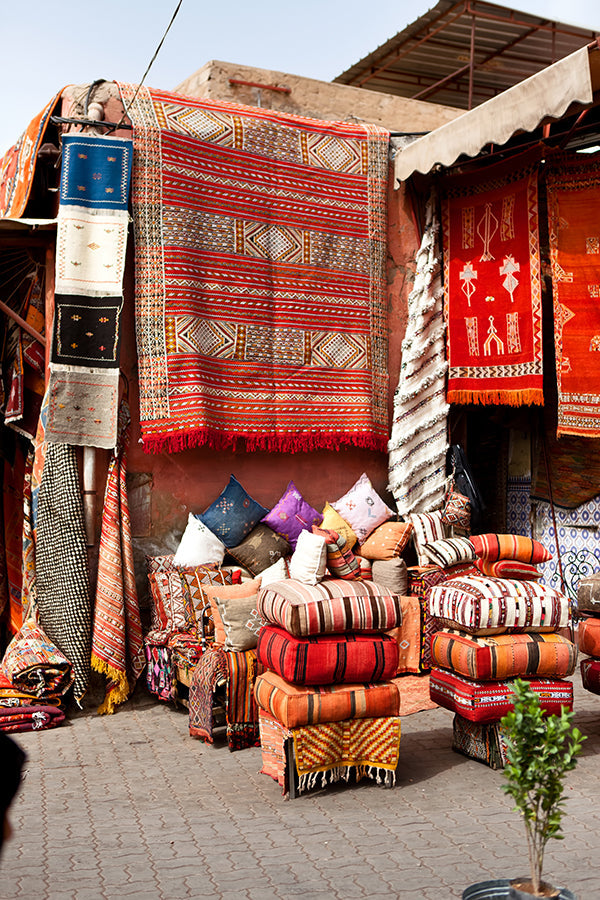 Vintage Moroccan rugs displayed in a Marrakech souk, handmade Berber wool carpets with rich colors and traditional patterns.