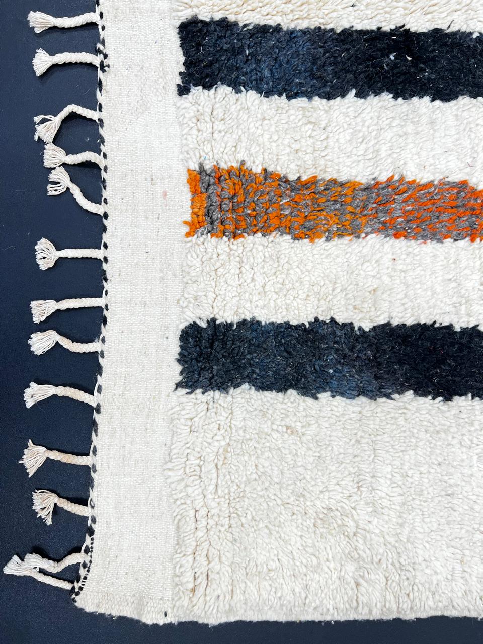 Handmade abstract Moroccan runner rug with black and burnt orange vertical stripes on a white wool base.
