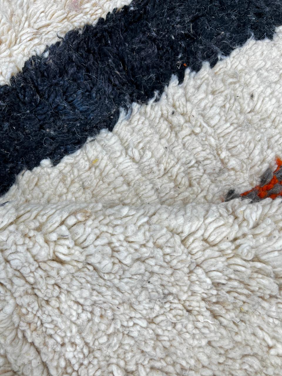 Handmade abstract Moroccan runner rug with black and burnt orange vertical stripes on a white wool base.