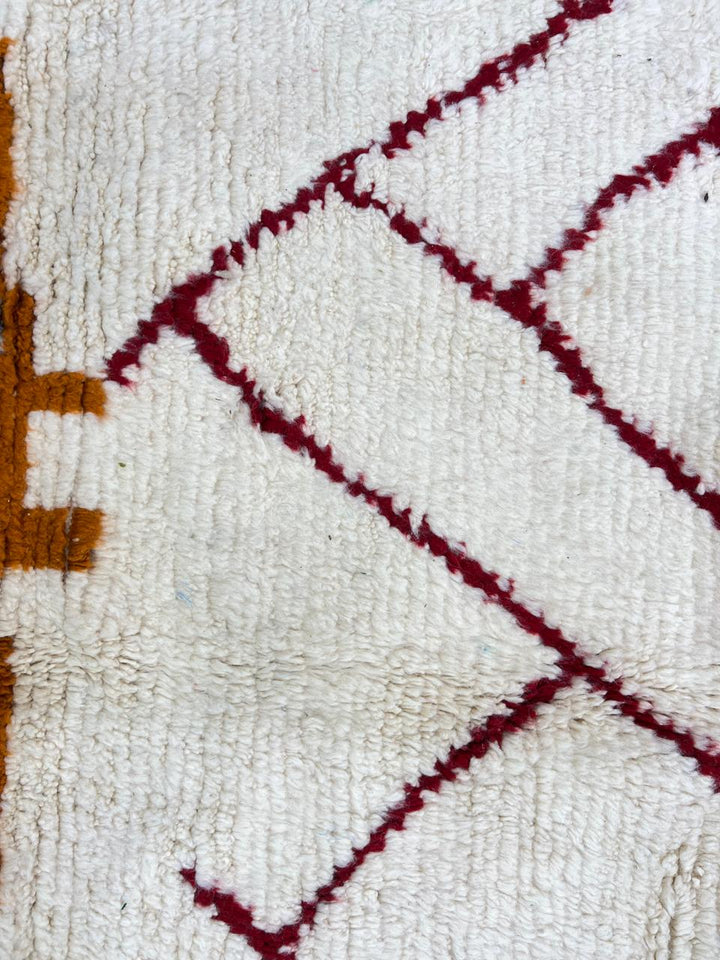 Handmade abstract Moroccan runner rug in white wool with flowing red line design, woven by Berber artisans.