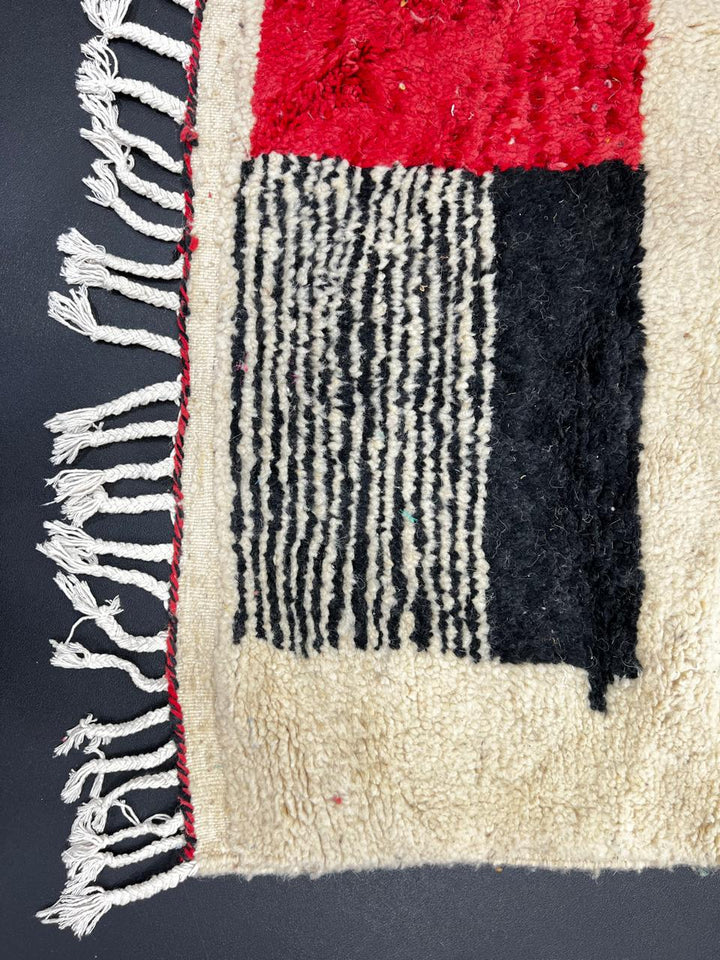 Handmade white Moroccan runner rug with red and black abstract geometric patterns in natural wool.