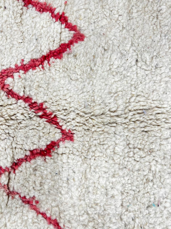 Handmade white Moroccan runner rug with red and black abstract geometric patterns in natural wool.