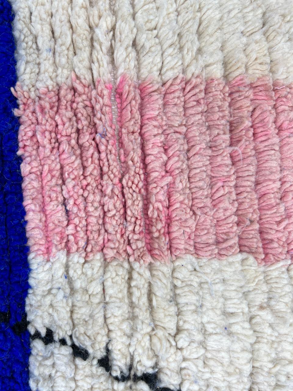 Round Moroccan wool rug with abstract blue, pink, white shapes and black line details.