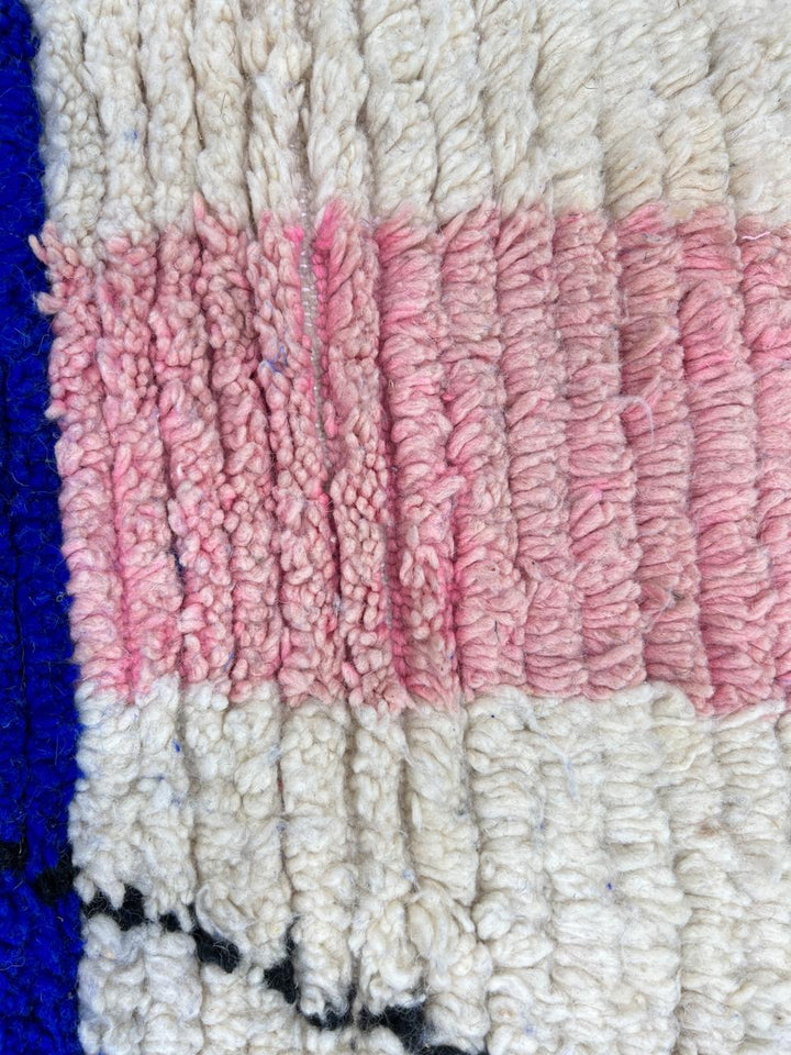 Round Moroccan wool rug with abstract blue, pink, white shapes and black line details.