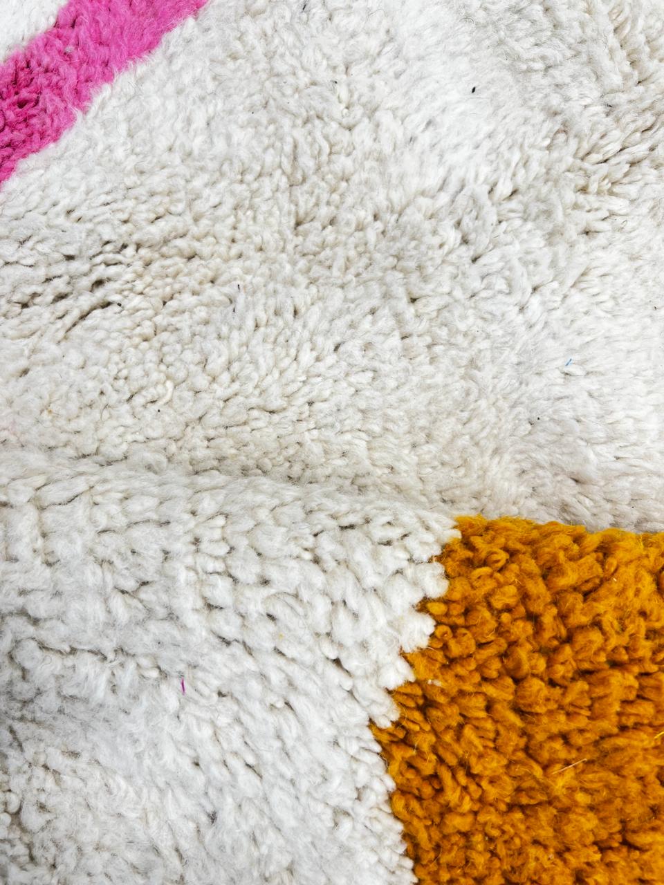 Handmade abstract Moroccan wool runner rug with cream base, pink line, blue shapes, green and mustard geometric accents.
