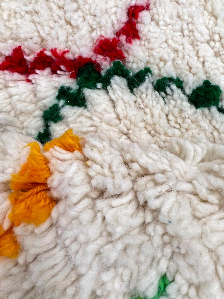 Handmade round Moroccan wool rug featuring an ivory background with colorful abstract Berber geometric patterns and a soft plush texture.