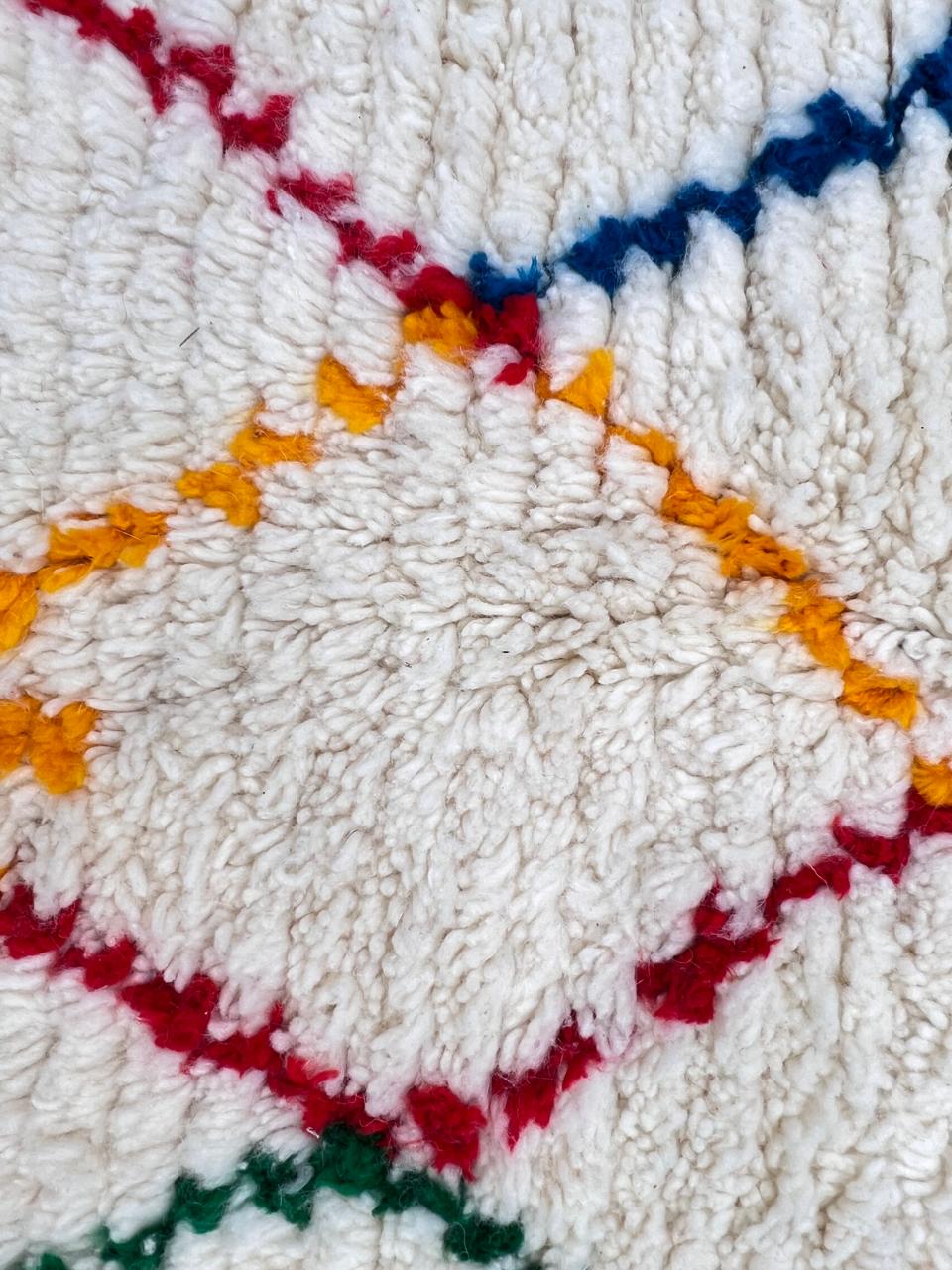 Handmade round Moroccan wool rug featuring an ivory background with colorful abstract Berber geometric patterns and a soft plush texture.