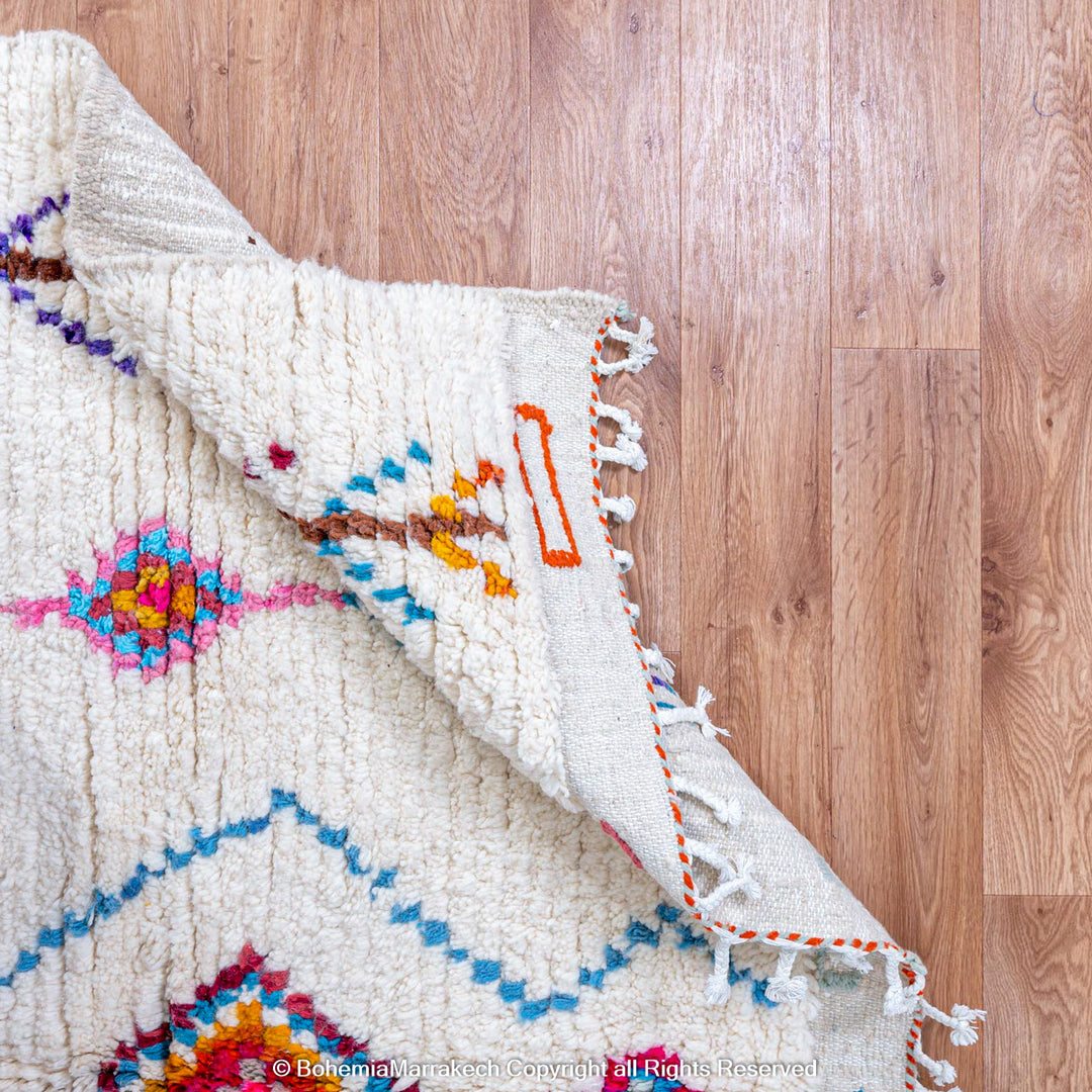 Handmade Beni Ourain Moroccan wool rug with colorful Berber diamonds on a white shag background
