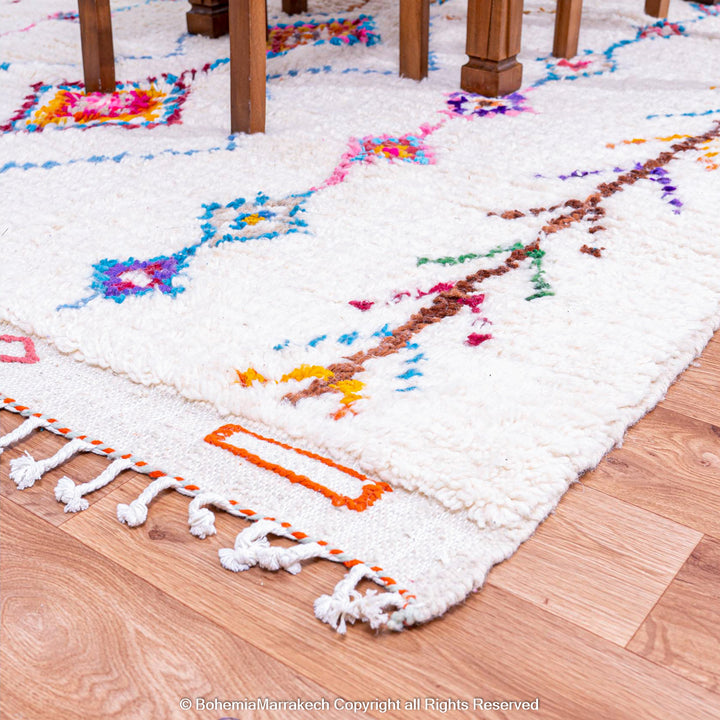Handmade Beni Ourain Moroccan wool rug with colorful Berber diamonds on a white shag background