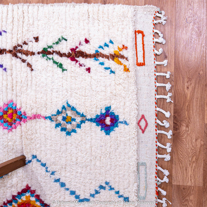Handmade Beni Ourain Moroccan wool rug with colorful Berber diamonds on a white shag background