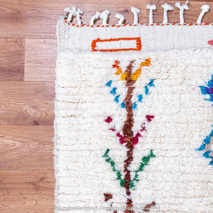 Handmade Beni Ourain Moroccan wool rug with colorful Berber diamonds on a white shag background