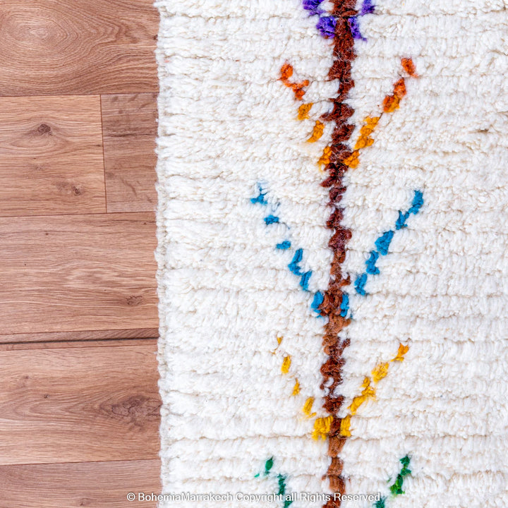 Handmade Beni Ourain Moroccan wool rug with colorful Berber diamonds on a white shag background