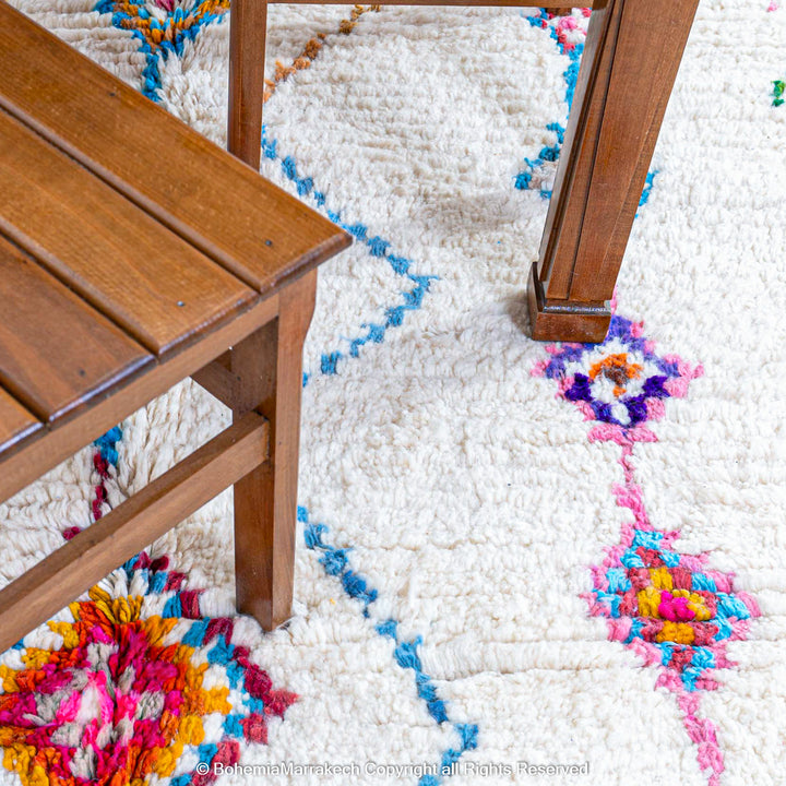 Handmade Beni Ourain Moroccan wool rug with colorful Berber diamonds on a white shag background