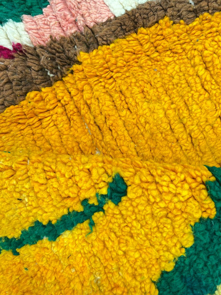 Handmade Moroccan runner rug with colorful abstract village-inspired motifs in mustard, teal, pink, black, and cream, crafted from natural wool.