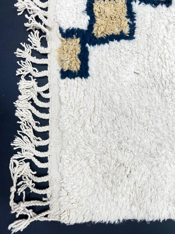 Beige Moroccan wool rug with black geometric diamond pattern, handmade by Berber artisans