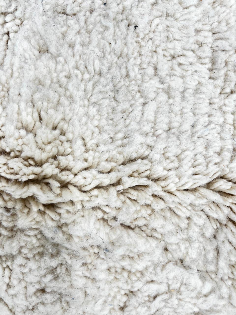 Beige Moroccan wool rug with black geometric diamond pattern, handmade by Berber artisans