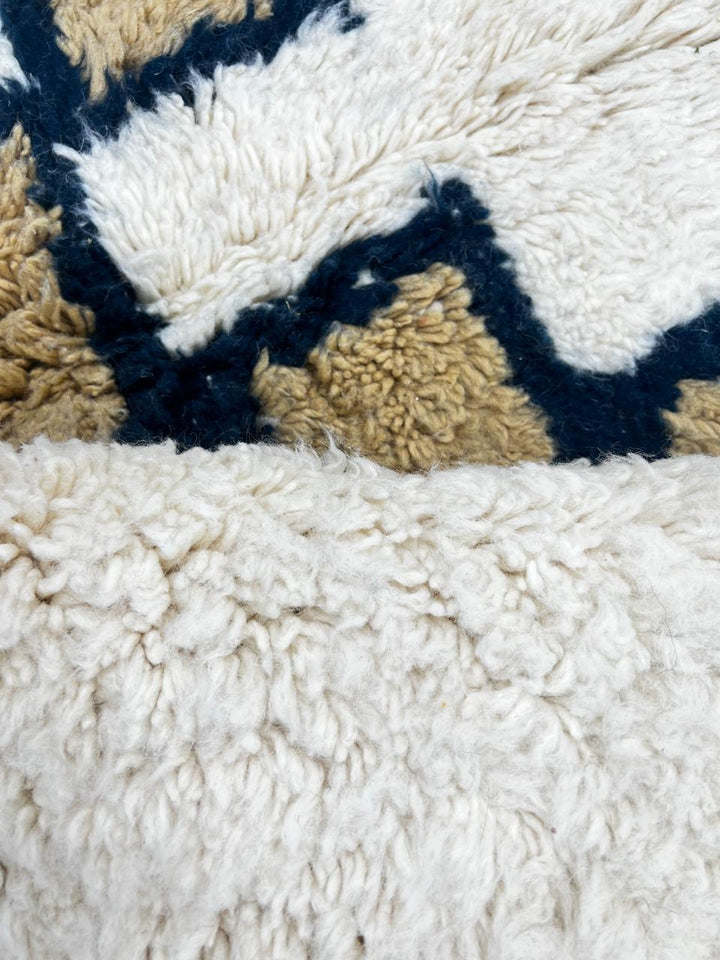 Beige Moroccan wool rug with black geometric diamond pattern, handmade by Berber artisans