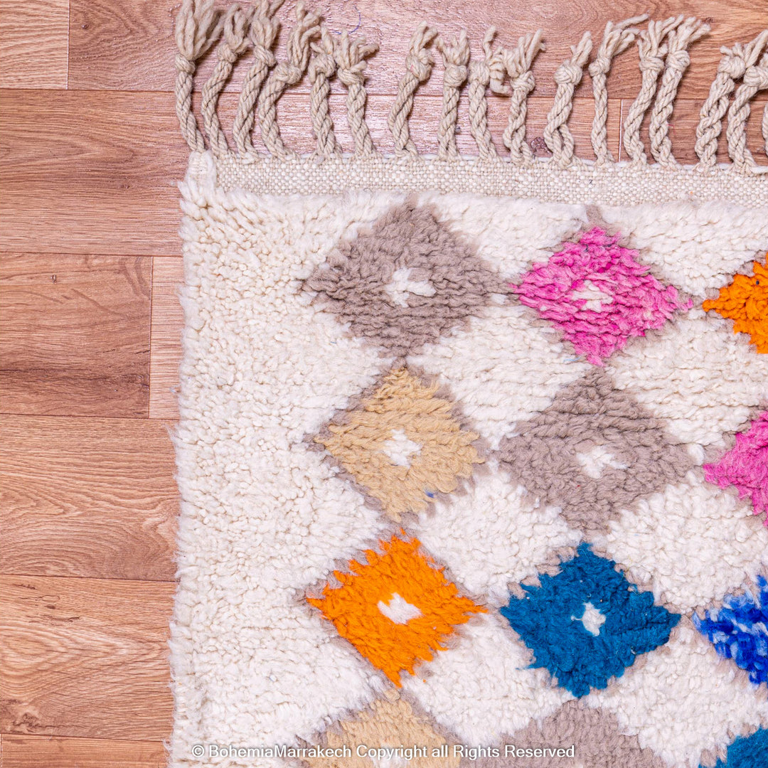 Handmade Moroccan rug with colorful diamond pattern on ivory wool background
