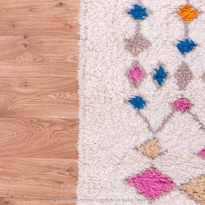 Handmade Moroccan rug with colorful diamond pattern on ivory wool background
