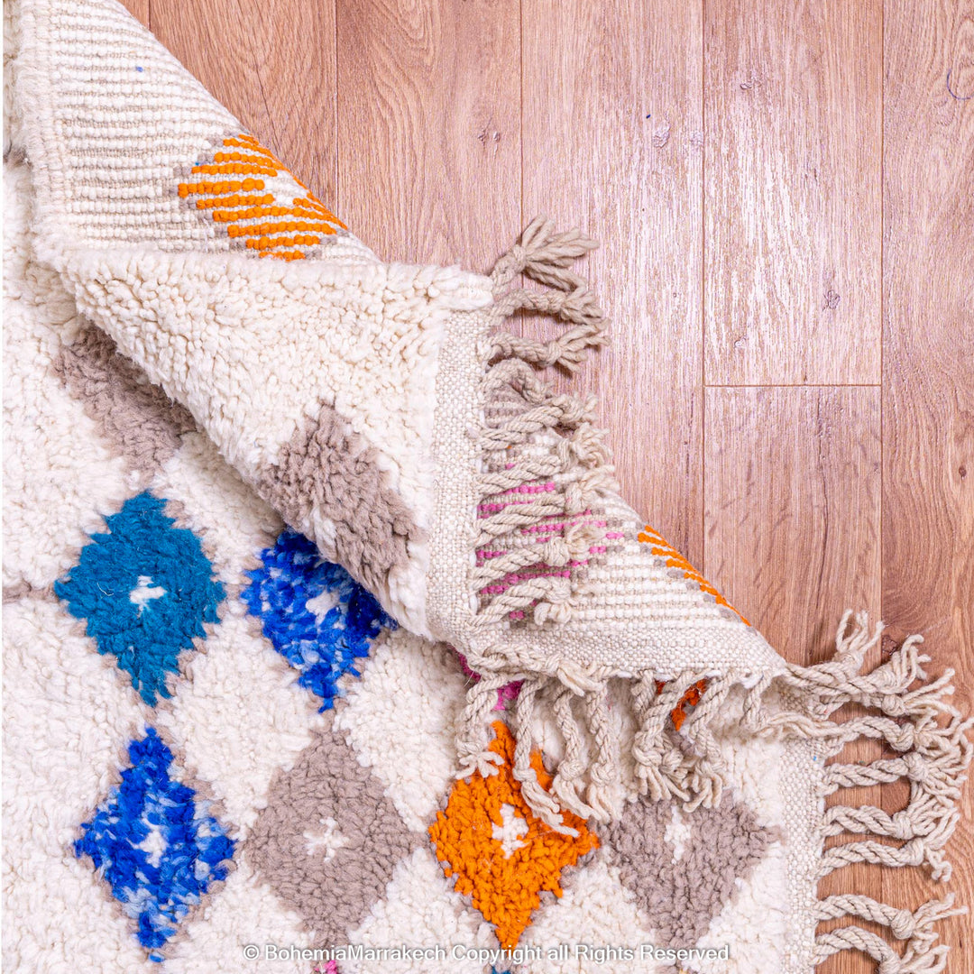 Handmade Moroccan rug with colorful diamond pattern on ivory wool background