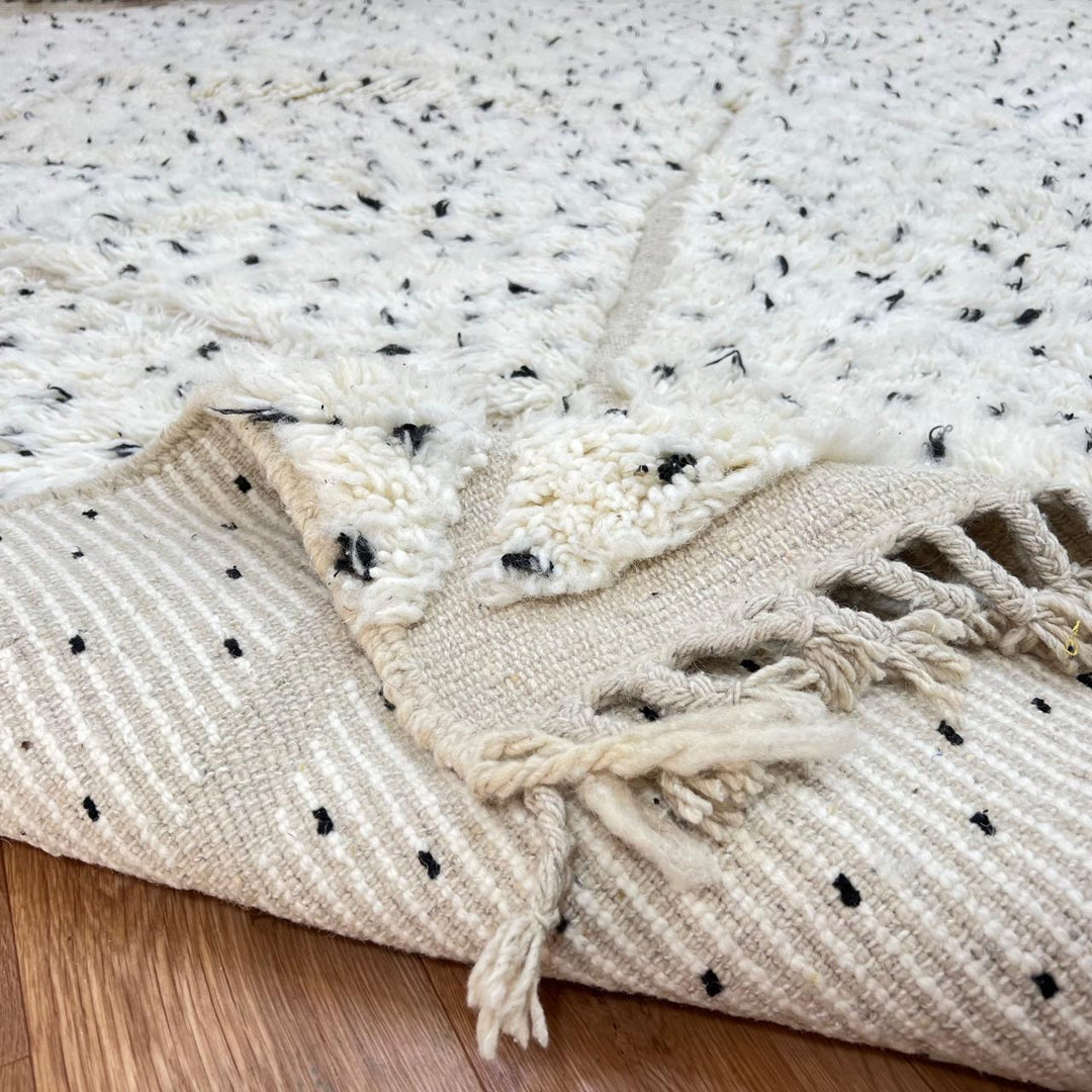 Handmade Moroccan wool rug with ivory base, diamond Berber pattern and subtle speckled accents. Soft plush texture, artisan crafted.