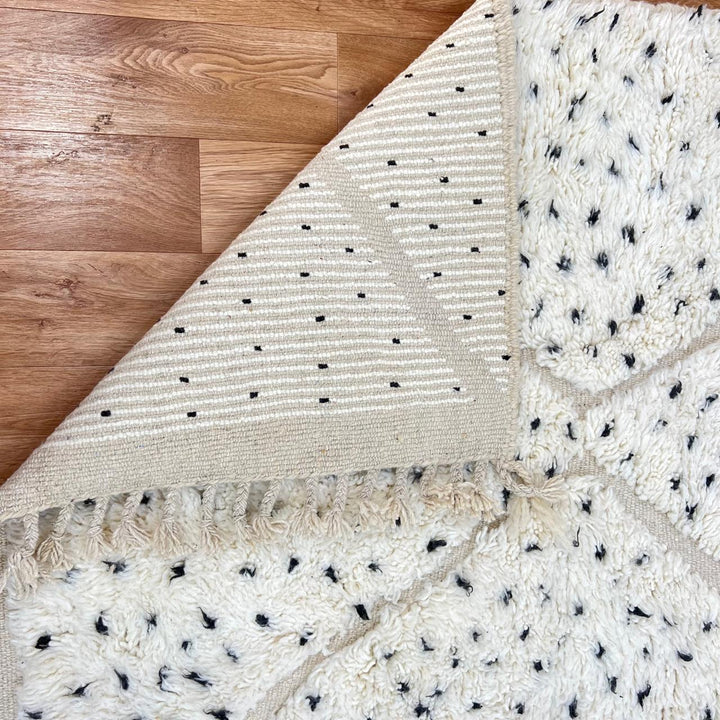 Handmade Moroccan wool rug with ivory base, diamond Berber pattern and subtle speckled accents. Soft plush texture, artisan crafted.