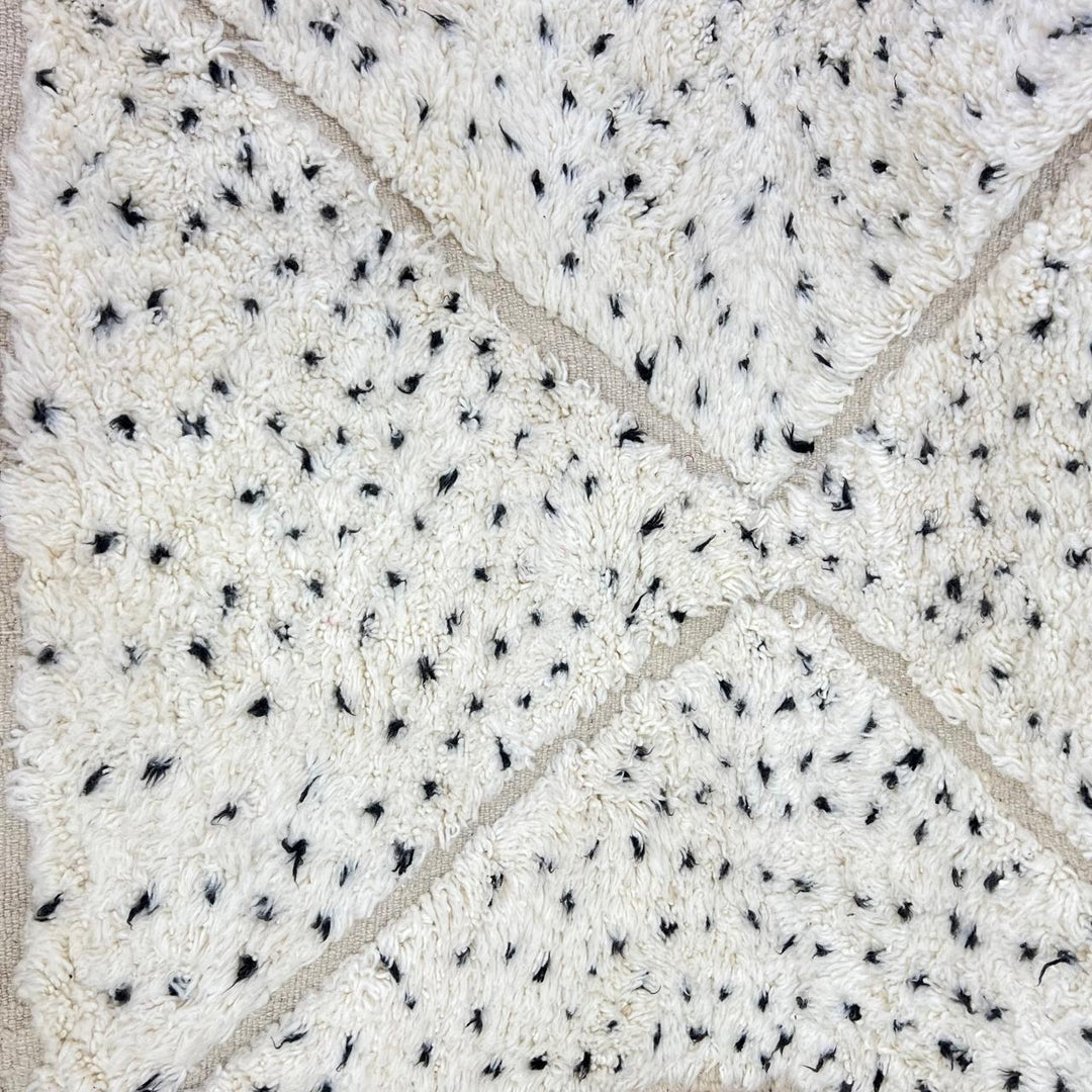 Handmade Moroccan wool rug with ivory base, diamond Berber pattern and subtle speckled accents. Soft plush texture, artisan crafted.