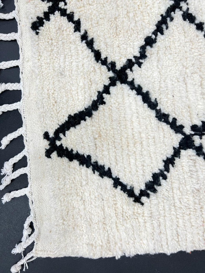 Handwoven Beni Ourain Moroccan wool rug with black diamond pattern on ivory background