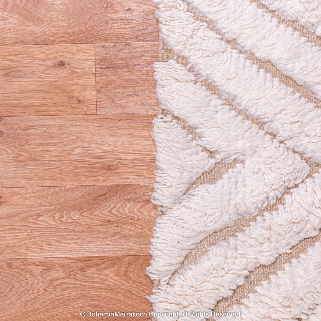 Close-up of a handmade Beni Ourain Moroccan rug with a white zigzag pattern on wooden flooring.