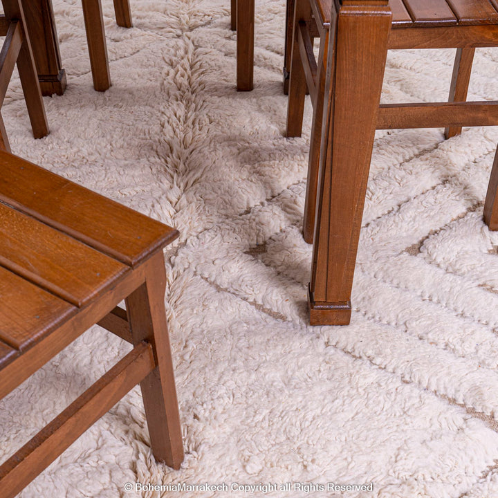 Handmade Beni Ourain Moroccan wool rug with geometric zigzag pattern under wooden chairs, perfect for a modern-boho aesthetic.