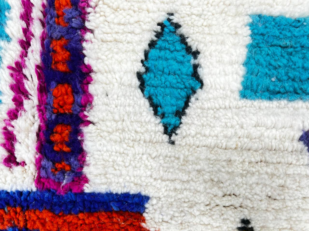 Handmade round Moroccan wool rug with colorful Berber symbols and tribal motifs on a natural white background.