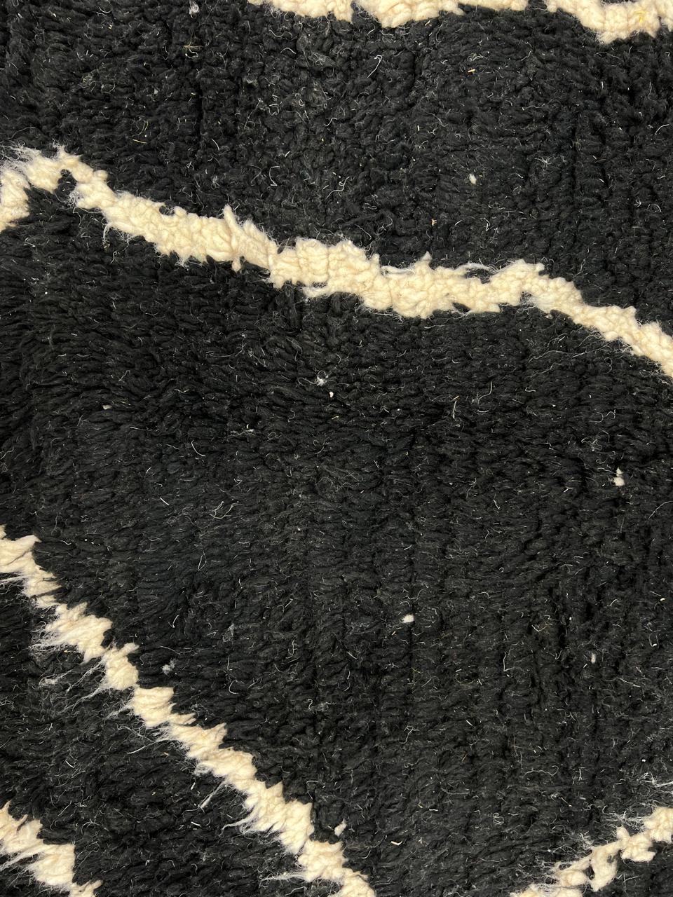 Round black Moroccan wool rug with beige abstract line design.