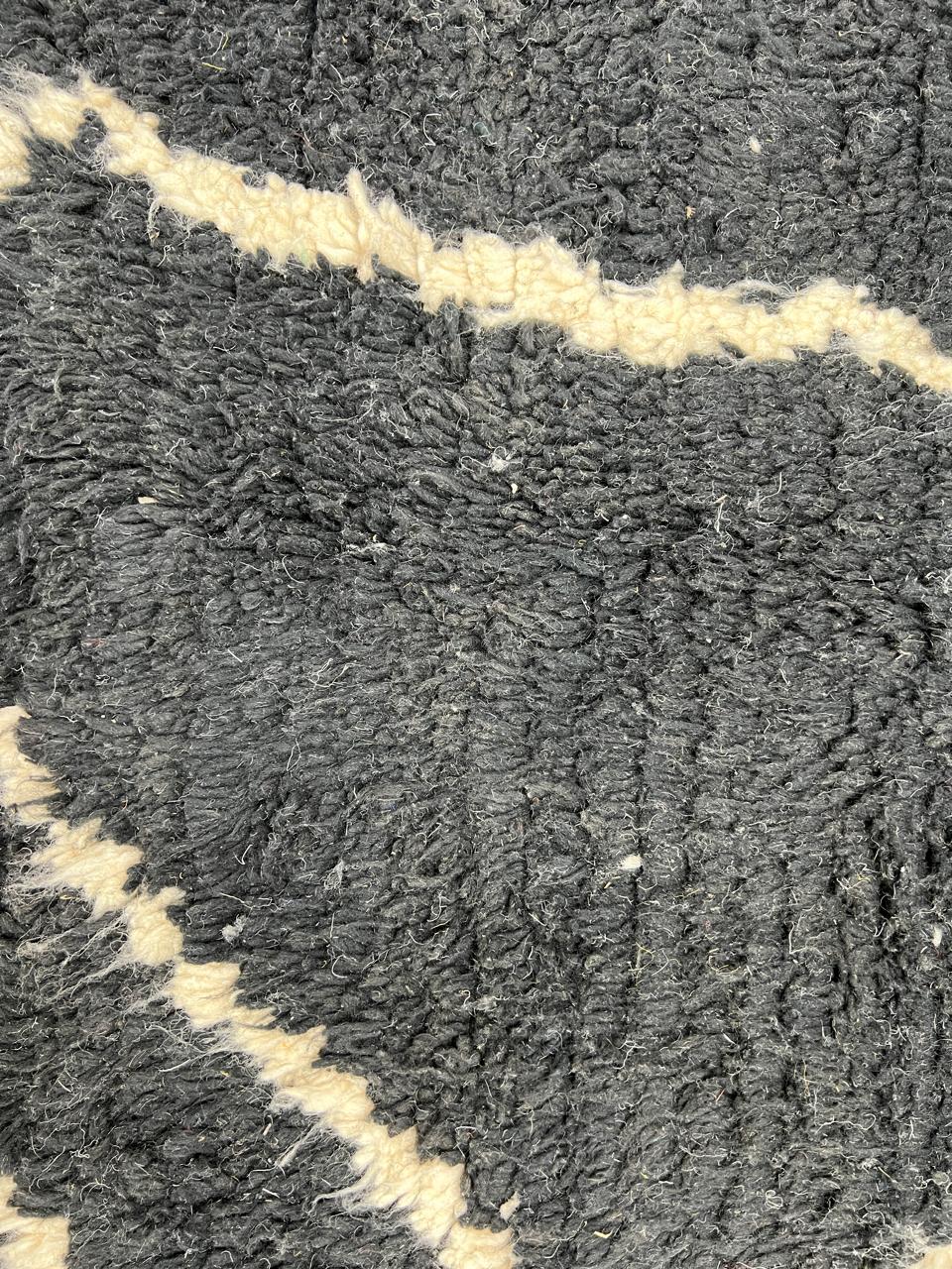 Round black Moroccan wool rug with beige abstract line design.