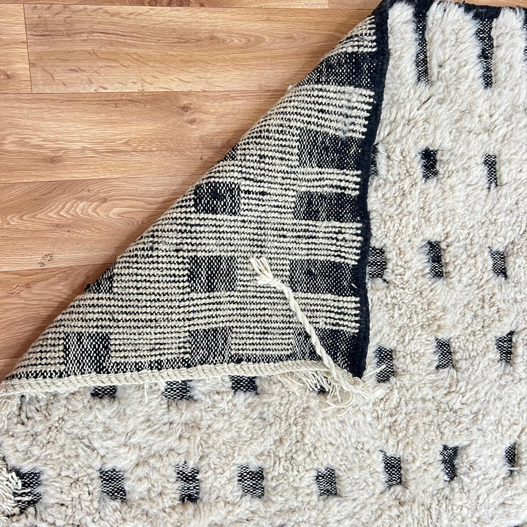 Handmade Moroccan wool rug with ivory base and subtle black square grid. Soft plush texture, minimalist style, artisan crafted.