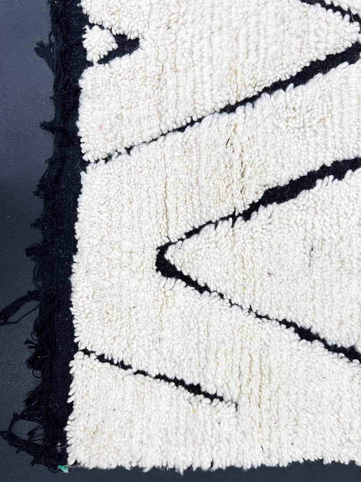 Black and white Moroccan runner rug with diamond geometric pattern made of handmade wool and black fringed ends