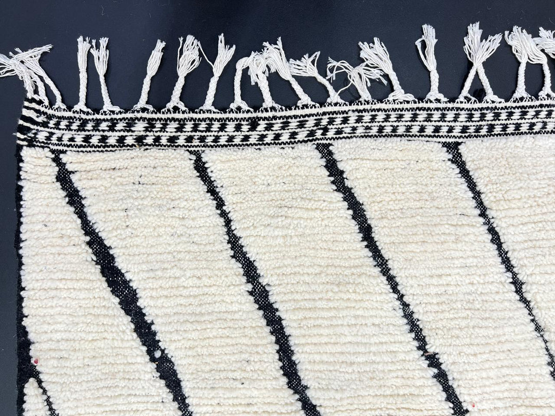 Handmade Moroccan runner rug with black geometric diamond pattern on a white wool background.