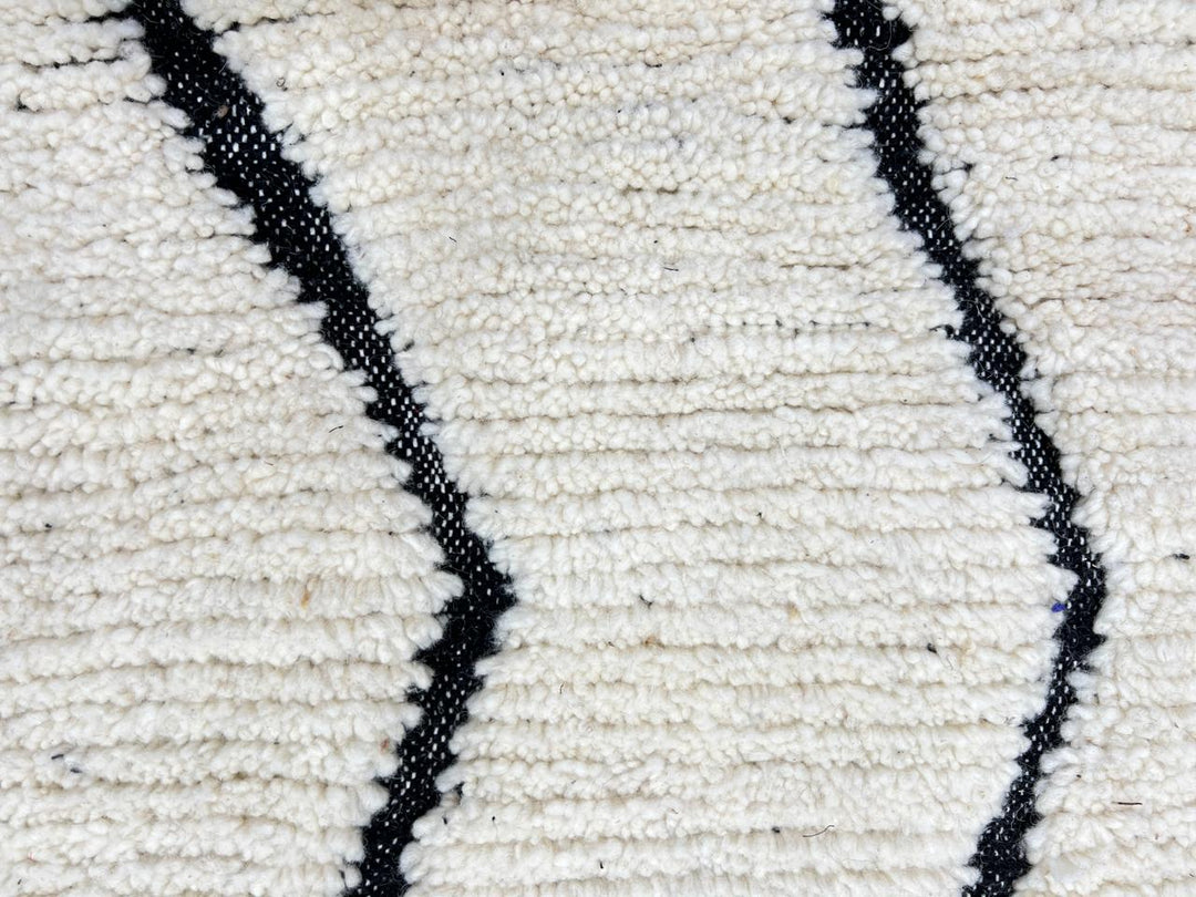 Handmade Moroccan runner rug with black geometric diamond pattern on a white wool background.