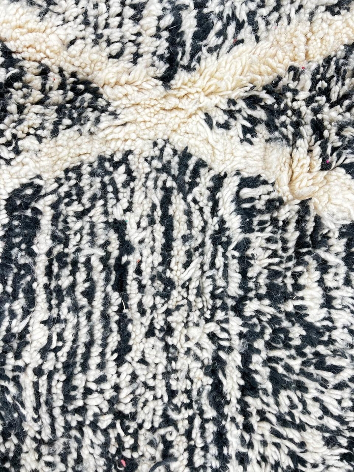 Black and white Moroccan wool runner rug with geometric diamond pattern and tassels, handmade by Berber artisans